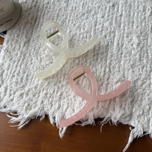 Close-up of cream and pink jelly acrylic hair claws on a textured knit background