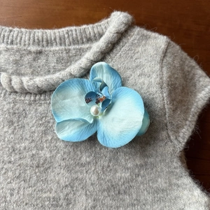 Detail of blue gradient orchid flower hair clip with a pearl on a gray knitted sweater