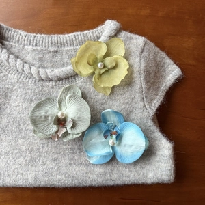 Detailed close-up of realistic phalaenopsis orchid hair clips with pearls on a sweater