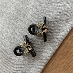Detailed macro view of two black mini hair claws with vintage gold bow and grey rhinestones