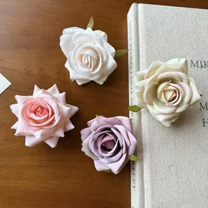Detail of four colorful silk rose heads on a vintage book for DIY decor projects