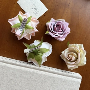 Detailed macro view showing diverse silk fabric roses with green leaves and metal clips