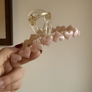 Dettaglio di una grande molletta per capelli trasparente con cuori rosa perlati
