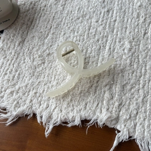 Close-up of cream beige hair claw clip with a minimalist twisted loop design and metal spring