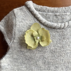 Green orchid flower clip with pearl center on sweater for a beach vacation look