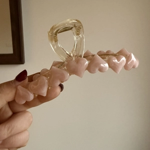Dettaglio della molletta per capelli in resina trasparente con cuori rosa e molla in metallo