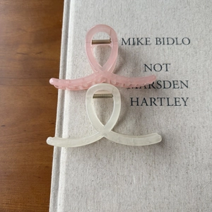 Detail view of pink and cream frosted hair claws with a cross ring design and metal spring