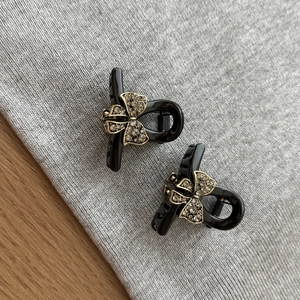 Elegant mini black bow hair clips with champagne rhinestones on grey fabric