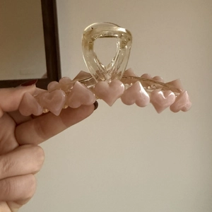 Dettaglio di cuori rosa 3D su una pinza per capelli ambra traslucida per acconciature