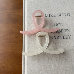 Detail view of pink and cream translucent acrylic hair claws with a twisted ribbon design