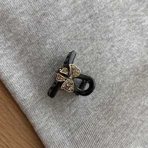 Mini black bow hair claw clip with dark sparkling crystals on a knit background