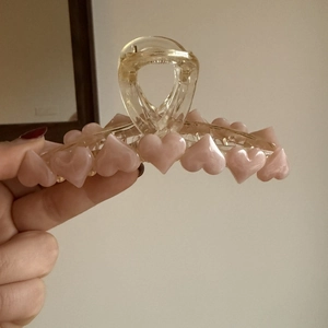 Dettaglio di un grande fermaglio per capelli in acrilico con cuori rosa e molla in metallo