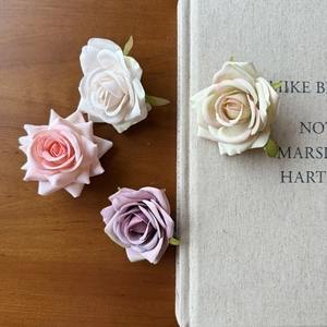 Close-up of artificial velvet rose flower heads in pink, white, and lilac on a wooden table