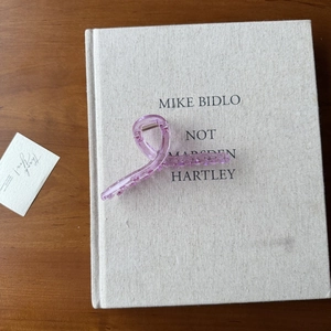 Vue détaillée d'une pince à cheveux en acrylique mauve posée sur un livre élégant