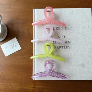 Vue détaillée de grandes pinces à cheveux en acrylique en quatre couleurs sur un livre