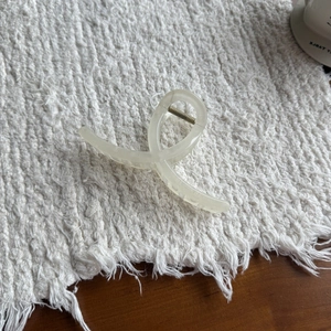 Elegant cream translucent shark hair claw clip with cross design on textured fabric