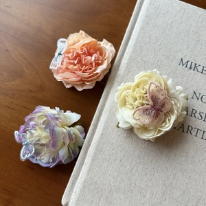 Detailed view of floral hair clips with embroidered butterflies on a wooden table