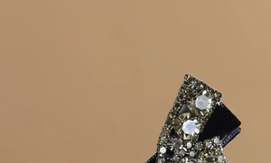Macro detail of elegant bow hair clip with champagne crystals on a dark base