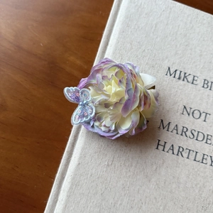 Close-up of sweet flower hair clip with purple petals and blue lace butterfly detail