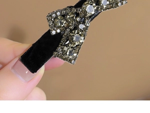 Macro detail of luxury black velvet bow hair clip with sparkling grey rhinestones