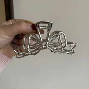 Détail d'une pince à cheveux papillon creuse argentée au design de lettres liquides