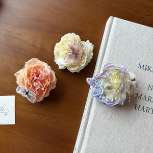 Detail view of floral hair clips with embroidered butterflies and layered fabric petals