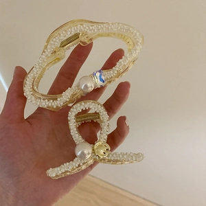 Detail showing two sizes of cream hair claws with pearls and crystal decorations