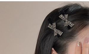 Close-up of sparkling rhinestone bow hair clips on hair with elegant velvet base