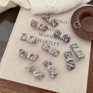 Detail of tweed bow hair clips with pearls, showing various colors and textured fabric