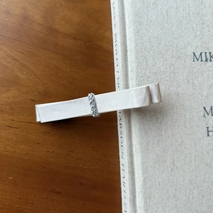 Detail of elegant cream fabric bow hair clip with sparkling rhinestone band on a book