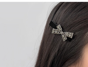 Close-up of sparkling bow hair clip with silver rhinestones on long dark hair