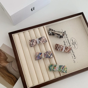 Detail of tweed bow hair clips with pearls on a jewelry tray in various colors