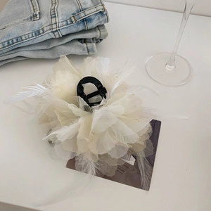Detail of cream feather flower hair claw clip with delicate fabric petals and gold hardware
