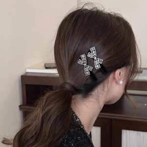 Detailed view of elegant velvet bow hair clips with rhinestones on a low ponytail hairstyle