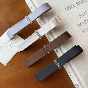 Detail showing set of four satin bow hair clips in gray, beige, brown and black colors
