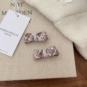 Detail of pink and black tweed bow hair clips with elegant white pearl center decorations