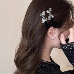 Detailed close-up of glittering rhinestone bow hair clips worn on side hair style