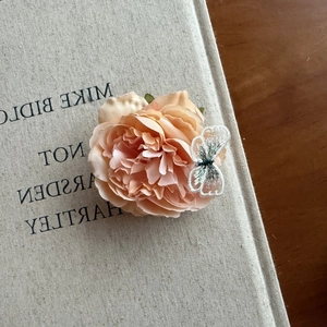 Elegant apricot rose hair clip with lace butterfly embroidery on a vintage book cover