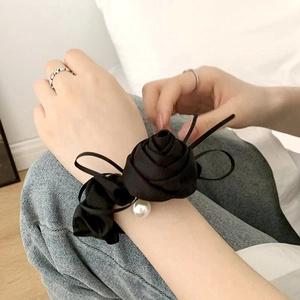 Close-up of elegant black satin rose hair scrunchie with center pearl detail worn on wrist