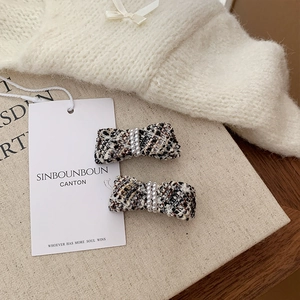 Detail of tweed bow hair clips with double row pearls on a soft knit background
