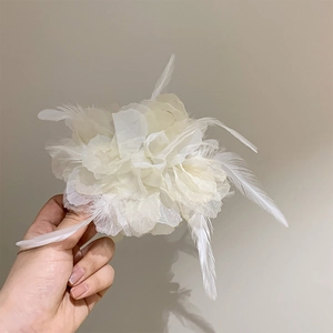 Macro shot of large white silk flower hair clip with soft feathers for bridal hairstyles