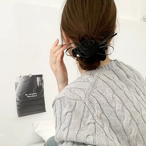 Detail view of a black satin rose hair scrunchie with elegant ribbons on a model's hair bun