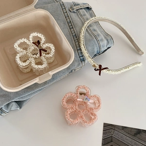 Close-up of floral hair claws and pearl headband set on a denim background
