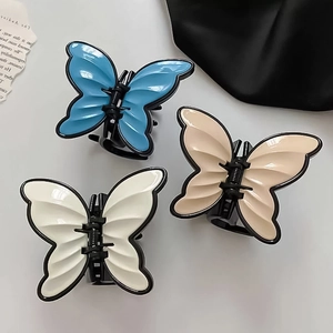 Detailed view of three French acrylic butterfly hair claws in blue, beige, and white