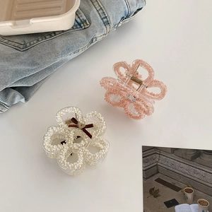 Detailed view of floral hair claws with pearls and ribbon on a clean Korean ins style background