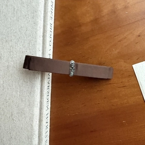 Elegant double-layered dark brown satin bow hair clip with rhinestone center on wooden desk