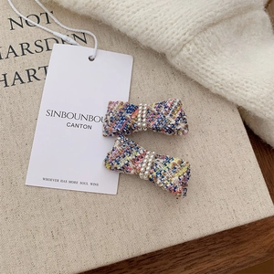 Close-up of elegant French style tweed bow hair clips with pearls on soft fabric