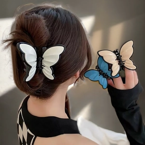 Detailed close-up of acrylic butterfly hair claws in white, blue and beige tones