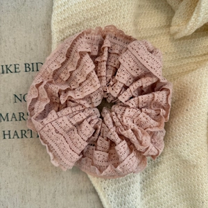 Close-up of pink layered lace scrunchie with detailed hollow embroidery and soft texture