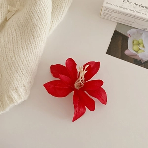 Détail d'une pince à cheveux fleur de magnolia en velours rouge aux pétales précis